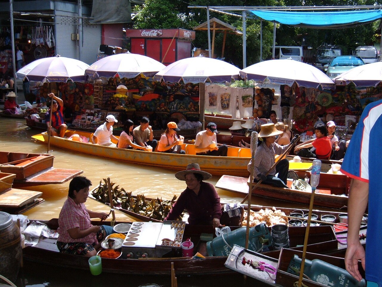 Boats selling goods and traveling along the canal at Damnoen Saduak Floating Market