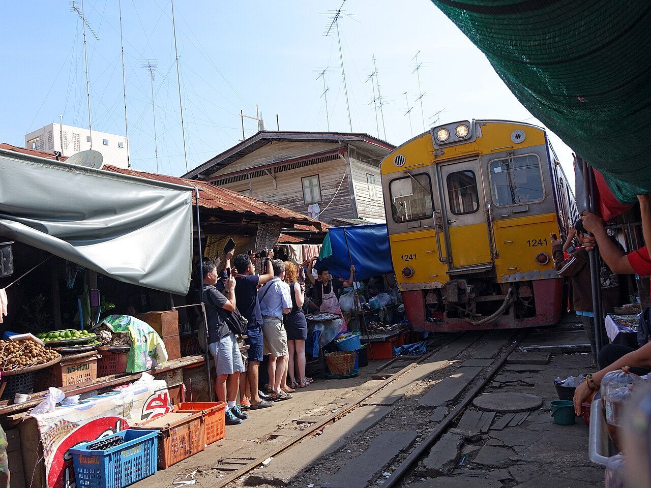 Yellow train and railway between the stalls at Mae Klong Railway Market