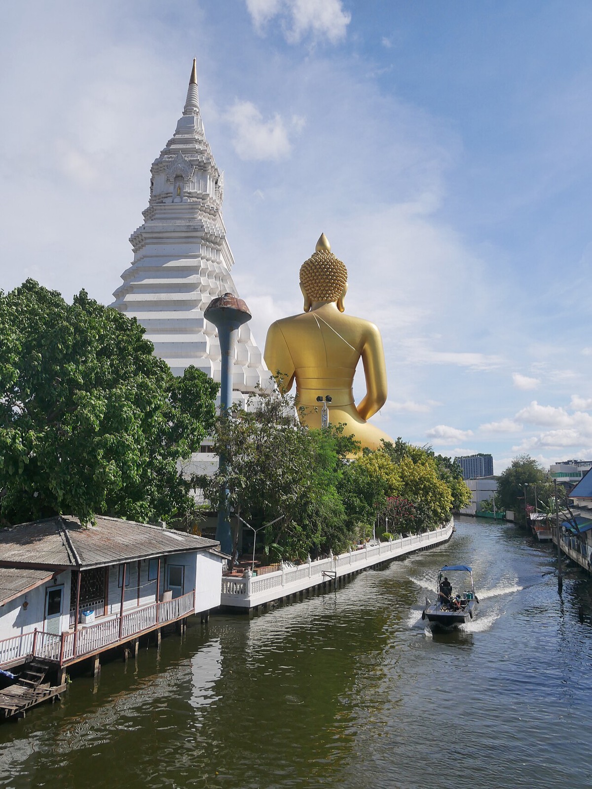 The large seated Buddha and white chedi at Wat Paknam, seen across a canal